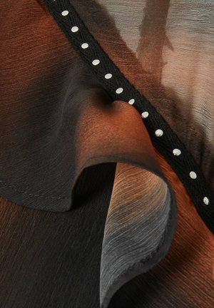 Tissu transparent avec des dégradés de noir, marron et gris, comportant une bande texturée noire avec de petites perles blanches régulièrement espacées.