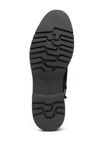 Semelle de chaussure en caoutchouc noir avec motif texturé à bande de roulement. Présente un design incurvé et lisse à l'avant-pied et un logo embossé près du talon.