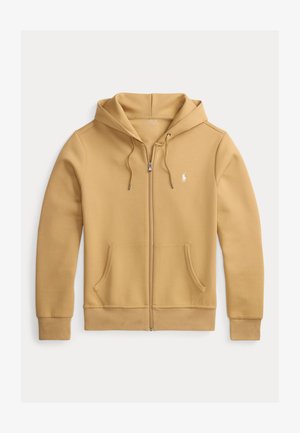 Iezsietojama kapuci jakas brūnā audumā, ar saistošu kapuci, kanguru kabatām un mazu logo uz krūtīm. Mīksta tekstūra un pieguļošs dizains.