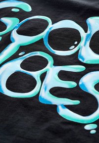 Modrý a zelený stylizovaný text s efektem kapek vody na černém textilním pozadí, detailní pohled.