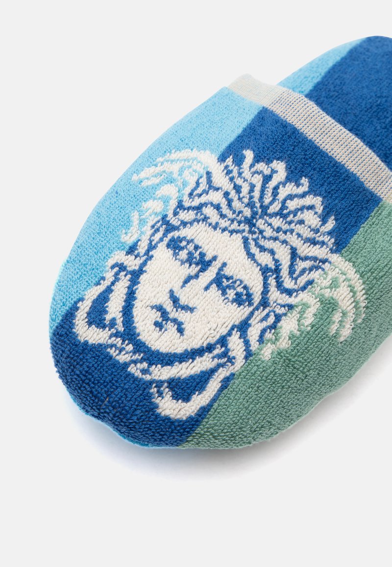 Sock with blue, light blue, and green stripes featuring a white and blue Medusa head design on the toe area.