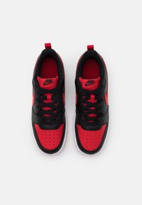 Nike sneakers featuring a black leather upper with red accents, mesh tongue, black laces, and perforated toe box on a white sole.