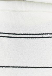 Biała tkanina o miękkiej, teksturowanej powierzchni, z dwoma poziomymi czarnymi paskami i wyższym dekoltem, podkreślająca prosty design.