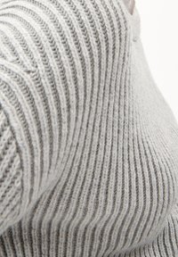 Suéter gris acanalado con un patrón de tejido texturizado. La tela es suave, con líneas verticales y un escote redondeado.