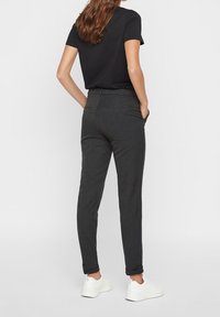 Gray tailored pants with a slim fit, rolled cuffs, and a flat waistband. Worn with a black short-sleeve top and white sneakers.