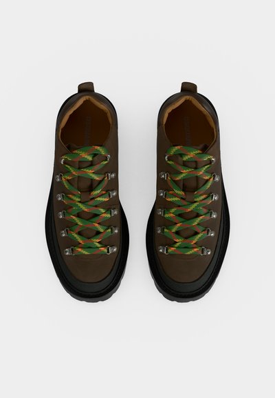 Paire de chaussures de randonnée marron avec des lacets verts et orange à motifs, semelles noires et œillets métalliques, vues de dessus sur fond blanc.