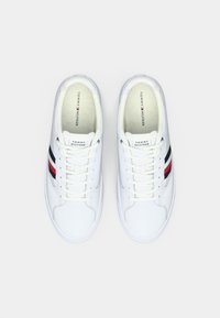 Adidași albi cu o textură netedă, având dungi orizontale negre și roșii, design cu șireturi și logo pe limbă.