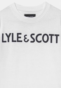 Camiseta blanca de manga corta con el texto negro y destacado "LYLE & SCOTT" en el frente. Tela simple y suave con un cuello redondo clásico.