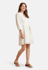 Weißes knielanges Kleid mit floraler Stickerei, Knopfleiste und 3/4-Ärmeln. Enthält einen gebundenen Taillengürtel und eine glatte Textur.