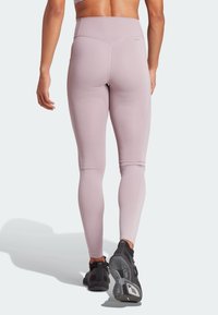 Vysoké sportovní legíny v jemně růžové barvě, vyrobené z elastického materiálu. Mezi vlastnostmi jsou hladký povrch a diskrétní švy.