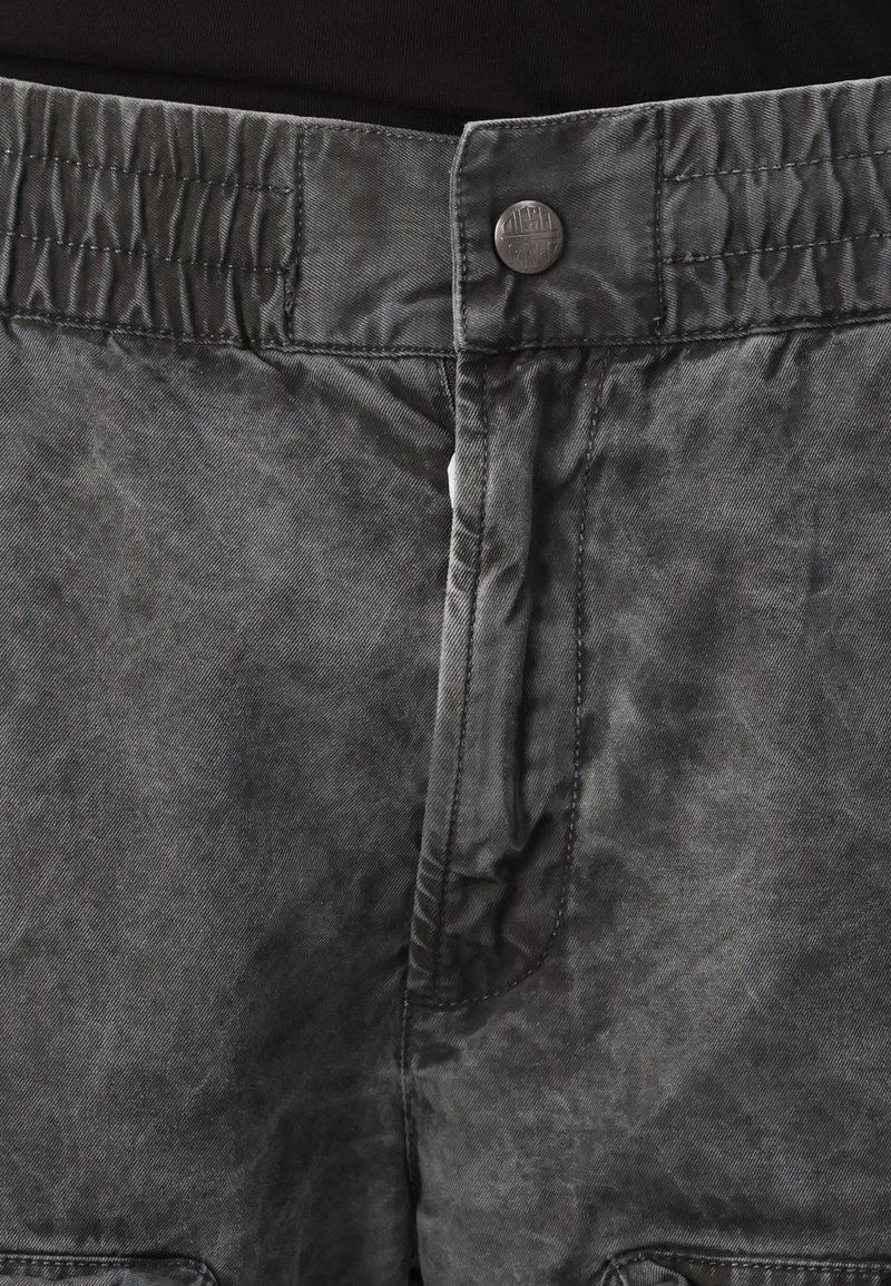 Czarne szorty o fakturowanej powierzchni z zapięciem na guzik i elastycznym paskiem w talii, z subtelnymi różnicami w odcieniu materiału i starannym szyciem.