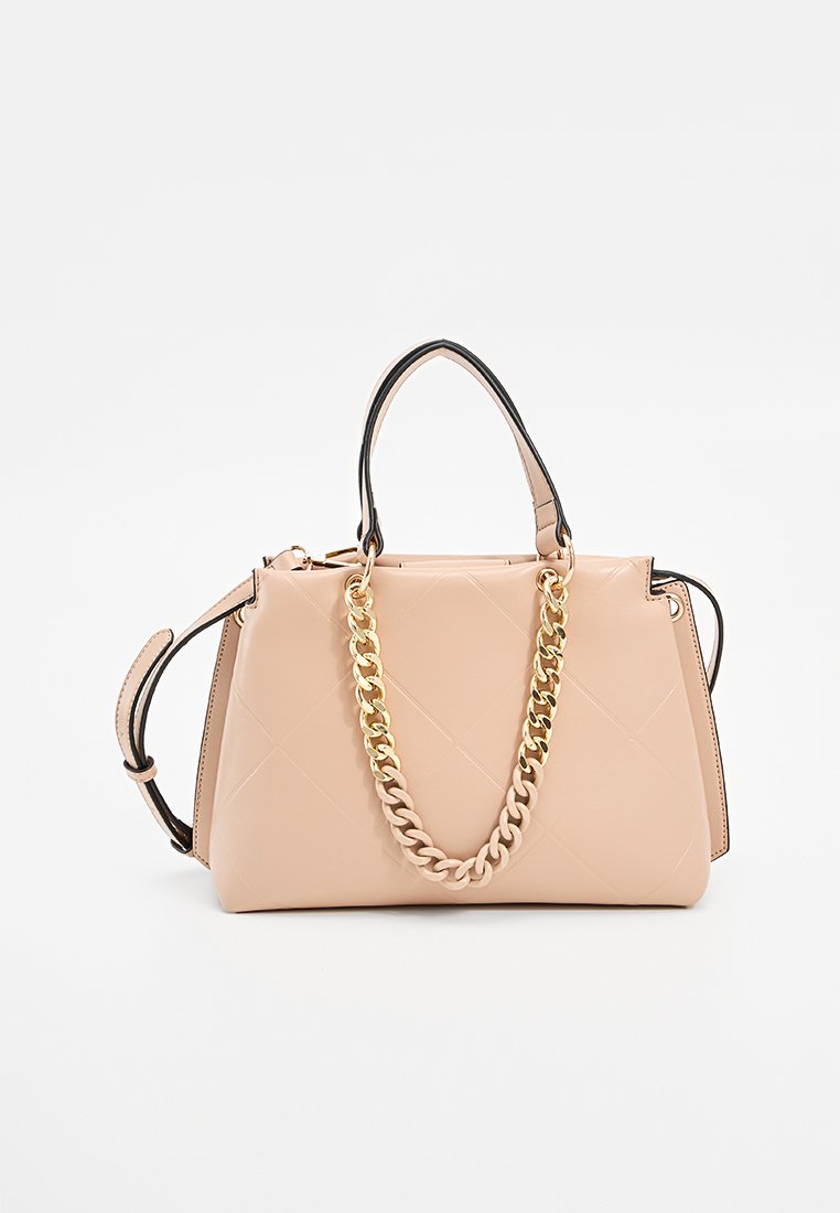 Sac à main en simili cuir beige avec texture matelassée, bord noir, poignées supérieures et accent en chaîne dorée épaisse. Design compact et structuré.