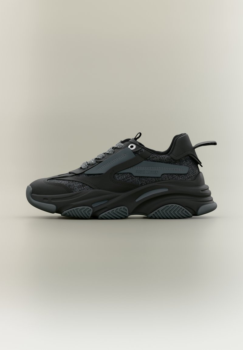 Baskets de sport noires et gris foncé avec semelle texturée, lacets à l'avant et languette au talon, vues de profil sur fond neutre.