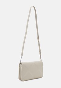 Borsa a spalla beige realizzata in materiale morbido e imbottito con un motivo trapuntato, dotata di una lunga tracolla regolabile e dettagli metallici.