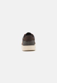 Mørk grå stoff-sneaker med brune semskede accenter, hvit gummisåle og teksturert bakparti. Designet med minimalistisk stil og søm detaljer.