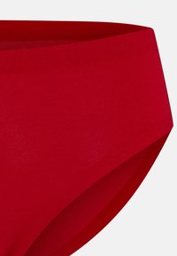 Slip in cotone rosso con una texture liscia, vita alta e design a copertura completa. Bordo senza cuciture per comfort e una vestibilità snella.