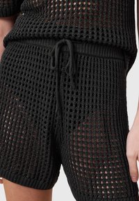 Zwarte gebreide shorts met een open mesh ontwerp, een elastische tailleband met trekkoord en een gestructureerd oppervlak.