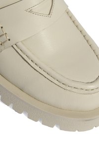 Crème leren instapper met een gladde textuur, voorzien van gestikte details, verhoogde accenten en een chunky rubberen zool met een profielpatroon.