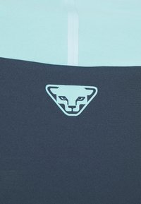 Σκούρο ναυτικό μπλε και ανοιχτό μπλε αθλητικός ύφασμα, με τριγωνικό λογότυπο που διαθέτει στυλιζαρισμένο πρόσωπο γάτας, λείο υφή και αντίθετες χρωματικές ενότητες.