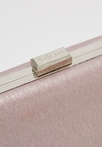 Gros plan sur une pochette rose scintillante avec un fermoir métallique argenté gravé du mot "MASCARA".