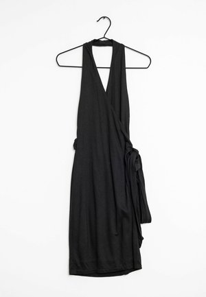 Robe portefeuille noire sans manches avec un décolleté en V profond suspendue à un cintre filaire noir sur fond blanc.