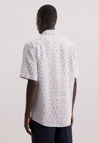 Korte mouw shirt in witte stof met een kleurrijk bloemenpatroon. Het ontwerp heeft een klassieke kraag en een afgeronde zoom.