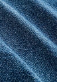 Sinine denimkangas nähtavate diagonaalsete kudumismustrite ja peente varjude ning tekstuuri ja voldikute esiletoomisega.