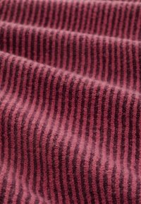 Textil in Dunkelrosa mit schmalen vertikalen Streifen, weiche Textur und leicht flauschiger Oberfläche, die ein gemütliches Erscheinungsbild schafft.