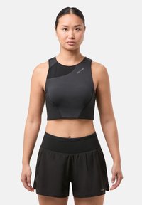 Top corto negro con un diseño ajustado, que presenta un hombro asimétrico único, combinado con pantalones cortos negros sueltos. Textura de tela suave.