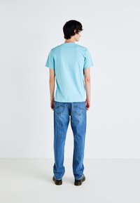 Light blue cotton t-shirt with a crew neck, paired with straight-leg blue denim jeans featuring back pocket stitching and a smooth finish.