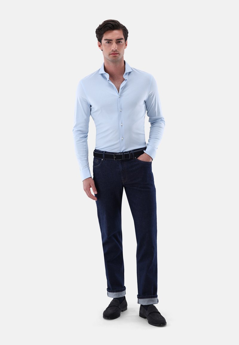 Helles blauer, langärmeliger Hemd, kombiniert mit dunklen, umgeschlagenen Jeans und schwarzen Schuhen. Einfaches Design, glatte Textur.