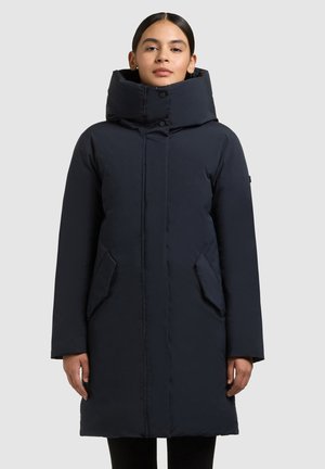 Dolga temno modra puhasta jakna z visokim ovratnikom, sprednjimi gumbi in stranskimi žepi. Gladek, izolativen material z ravnim krojem.