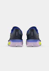 Las zapatillas de correr Nike cuentan con una parte superior de color azul oscuro, una suela morada en degradado y un acento amarillo neón. El diseño es elegante con un acabado texturizado.
