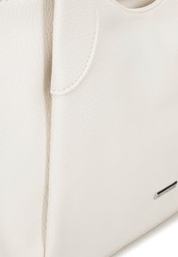 Borsa a tracolla in pelle bianca con finitura tessurizzata, manici curvi e un accento metallico minimal. Presenta cuciture visibili e un design moderno.