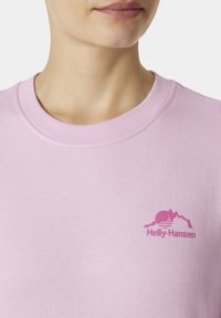 Jasnoróżowa bawełniana koszulka z okrągłym dekoltem, z różowym graficznym logo gór i słońca na lewej piersi.