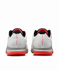 Zapatillas deportivas blancas con una parte superior texturizada, cuello negro y un acento rojo brillante en el talón. Presenta la marca "VAPOR" en rojo.