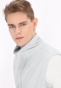Hellgraue Fleece-Weste mit hohem Kragen und einem Frontreißverschluss. Glatte Textur, ohne Ärmel und mit minimalen Nähdetails.