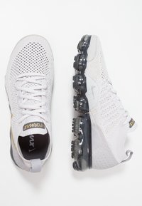 Witte sport sneakers met een bovenwerk van mesh, grijze accenten en een slank ontwerp. Voorzien van transparante luchtkussen en een gestructureerde zool voor grip.