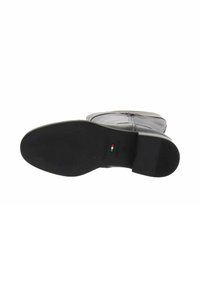 Suela de bota de cuero negro con acabado texturizado, tacón plano y dibujo mínimo. Incluye el logotipo de la marca y detalle de la bandera italiana.