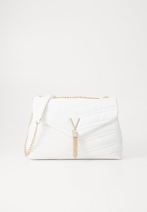 White quilted handbag featuring a fold-over flap, gold chain strap, and a metallic tassel accent with a logo. Smooth texture, rectangular shape.