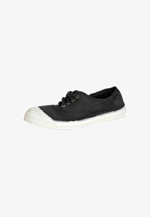 Zapatillas de lona negra con puntera y suela de goma blanca. Cuenta con cordones negros y ojales de latón, tela texturizada y forma redondeada.