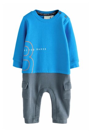 Niebieski top z długim rękawem z napisem „By Ted Baker” i pomarańczowym numerem 3, przymocowany do szarych spodni z bocznymi kieszeniami i zatrzaskami.
