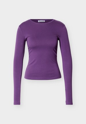 Bluza mov cu mâneci lungi, cu decolteu rotund, croială strâmtă și textură netedă. Țesătura pare moale și elastică, potrivită pentru purtarea casual.