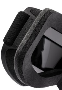 Juoda ergonominė įranga su lygiu paviršiumi, tekstūruotais kraštais, lipnia juosta ir "MADE IN ITALY" etikete. Būdingos apvalios formos ir elegantiškas dizainas.