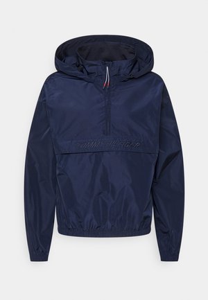 Laivastonsininen tuulitakki, jossa on puolivetoketju, säädettävä huppu, elastiset hihansuut ja brodattu "TOMMY HILFIGER" -logo edessä. Kevyt materiaali.