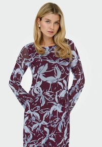 Gėlėtas ilgomis rankovėmis suknelė tamsiai burgundiško atspalvio, su šviesiai mėlynomis botaninėmis raštais. Pagaminta iš permatomo, lengvo audinio.