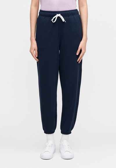 Marinesvettebukser med elastisk midjebånd og justerbar hvit snor; kantede ermer; kombinert med hvite joggesko og lyse sokker.