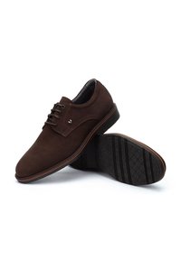 Brązowe zamszowe buty do dress code'u z gładkim wykończeniem, okrągłym noskiem, wiązanym przodem oraz kontrastującą gumową podeszwą z wzorzystym bieżnikiem.
