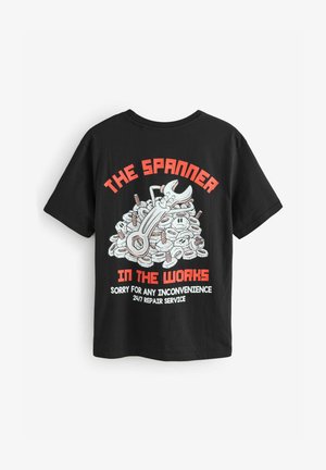 Must noirist T-särk, millel on koomiksiteemaline pilt mutrist, mida ümbritsevad poldid ja mutrid, koos punase ja valge tekstiga "TÖÖTAV MUTTER".