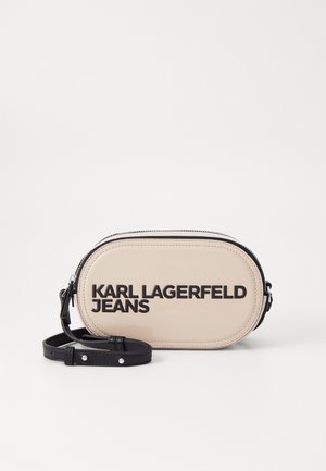 Sac oval en matériau beige brillant. Présente un texte en noir audacieux "KARL LAGERFELD JEANS" et une bandoulière noire amovible. Fermeture éclair.